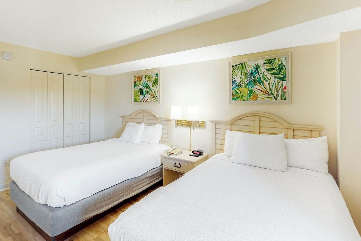 Une chambre d’hôtel avec deux lits, une armoire et des œuvres d’art accrochées aux murs.