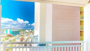 Un balcón con vista a un paisaje urbano, que incluye edificios y una carretera.