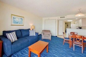A living room with a sofa, armchairs, a coffee table, and a dining area with chairs and a table. - Bay Watch Resort 0620 (North Myrtle Beach)