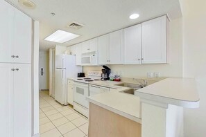 A compact kitchen with white cabinets, a microwave, a stove, and a sink. - Bay Watch Resort 0620 (North Myrtle Beach)
