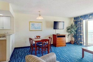 A room with a dining table, chairs, a television, a cabinet, a sofa, and a potted plant. - Bay Watch Resort 0620 (North Myrtle Beach)