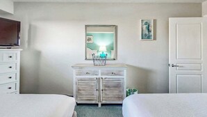 Ein Hotelzimmer mit einem Bett, einem Schminktisch, einem Fernseher, einem Spiegel und einer Tür.