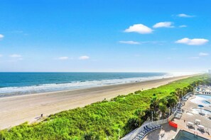 A beach view with a pool area and lounge chairs. - Bay Watch Resort 0603 (North Myrtle Beach)