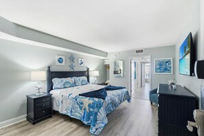 A bedroom with a bed, bedside tables, a dresser, and artwork on the walls. - Bay Watch Resort 0603 (North Myrtle Beach)