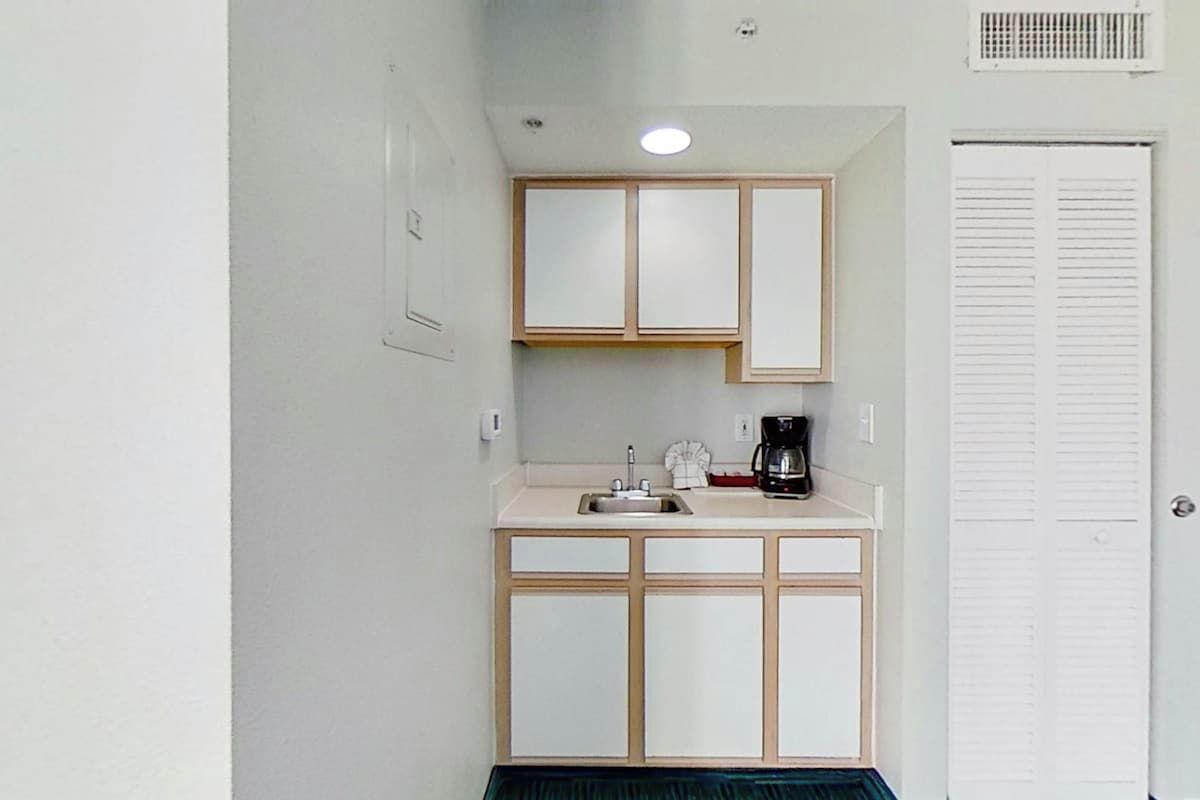 A compact kitchenette with a sink, a coffee maker, and a small countertop.