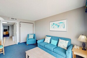 Ein Zimmer mit einem blauen Sofa, einem Holztisch und einem gerahmten Bild an der Wand.