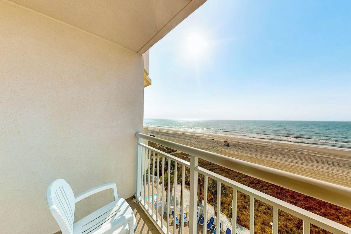 En balkon med udsigt over strand og hav.
