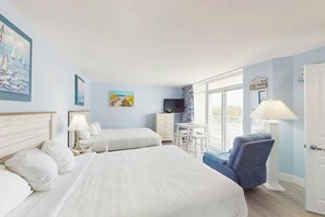 Une chambre d’hôtel avec deux lits, un bureau, une chaise, une télévision et une fenêtre donnant sur un paysage agréable.