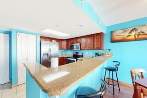 Eine Küche mit Granit-Arbeitsplatte, Edelstahlgeräten, Holzschränken und einer blauen Akzentwand.