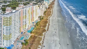 Ein Küstenhotel mit mehreren Hochhäusern, einer Strandpromenade und einem Poolbereich.