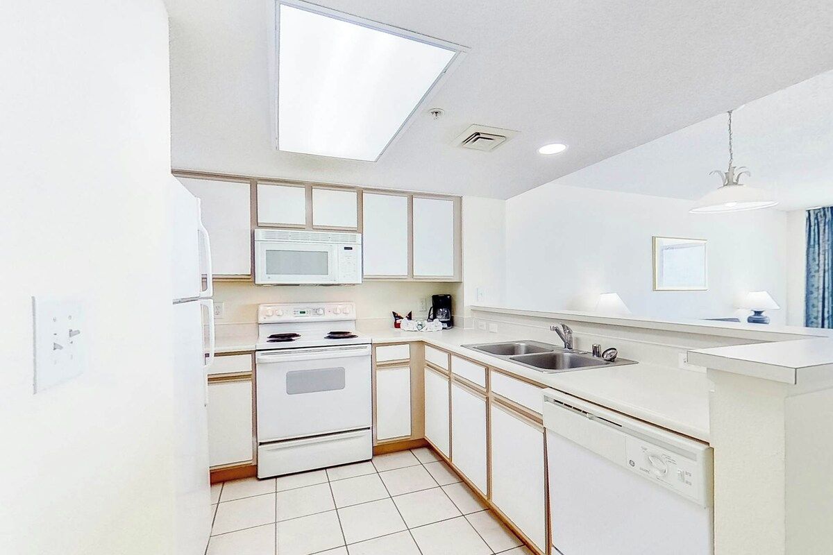Una cocina moderna con armarios blancos, microondas, estufa y lavaplatos.