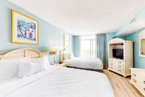 Une chambre d’hôtel avec deux lits, une télévision, une commode et un tableau au mur.