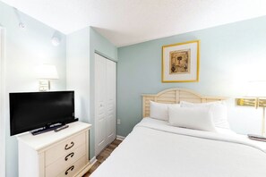 A hotel room with a bed, a TV on a dresser, a wardrobe, and a framed picture on the wall. - Bay Watch Resort 0717 (North Myrtle Beach)