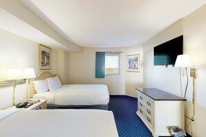 A hotel room with two beds, a desk, a dresser, a TV, and a window with curtains. - Bay Watch Resort 0714 (North Myrtle Beach)