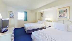 Ett hotellrum med två sängar, en TV, ett skrivbord och konstverk på väggarna.