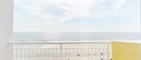A balcony with a view of the beach and ocean.