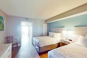 A hotel room with two beds, a desk, a chair, and a nightstand with a lamp. - Bay Watch Resort 0804 (North Myrtle Beach)