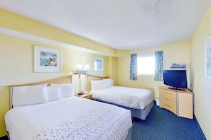 A hotel room with two beds, a television, a desk with drawers, and two framed pictures on the wall. - Bay Watch Resort 0807 (North Myrtle Beach)
