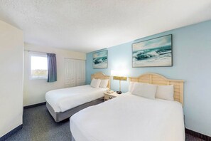 A hotel room with two beds, a window with curtains, and artwork on the wall. - Bay Watch Resort 0815 (North Myrtle Beach)