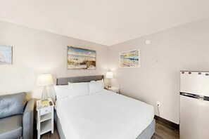 Ein Hotelzimmer mit einem Bett, Nachttischen, einer Lampe, einem Kühlschrank und Wandbildern.