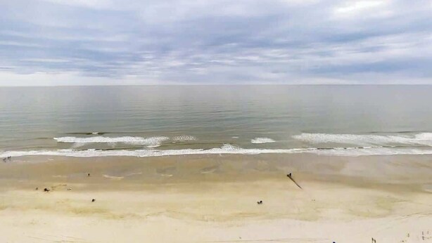 Ein Strand mit breitem Sandstrand und ruhigem Wasser.