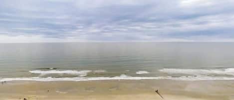Una playa con una extensa orilla arenosa y aguas tranquilas.