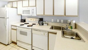 A kitchen with white appliances, a dishwasher, a sink, and cabinets above the countertop. - Bay Watch Resort 0814 (North Myrtle Beach)