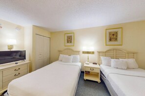 Une chambre d’hôtel avec deux lits, une télévision, un bureau et une armoire.