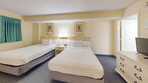 Ein Hotelzimmer mit zwei Einzelbetten, einem Schminktisch, einem Fernseher und einer Tür zu einem weiteren Raum.