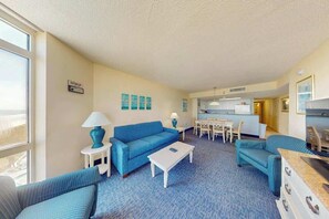 Ein Hotelzimmer mit einem blauen Sofa, einem weißen Couchtisch und einer Essecke mit Tisch und Stühlen.