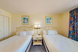 A hotel room with two beds, a nightstand with lamps, and two framed pictures on the wall. - Bay Watch Resort 0817 (North Myrtle Beach)