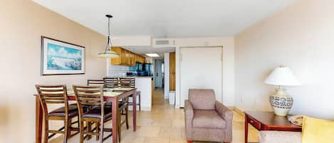 Una sala de estar con comedor, un sofá, una lámpara y una cocina al fondo.
