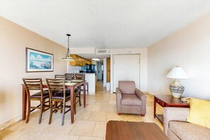 A living room with a dining area, a sofa, a lamp, and a kitchen in the background. - Bay Watch Resort 0819 (North Myrtle Beach)