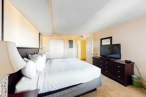 Een hotelkamer met een bed, een televisie, een dressoir en een lamp.