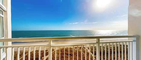 A balcony with a view of the ocean and beach.