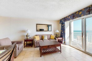 A living room with a sofa, a coffee table, and a TV. There is a balcony with a view of the sea. - Bay Watch Resort 0819 (North Myrtle Beach)