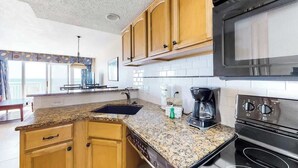 Eine Küche mit Granit-Arbeitsplatten, Holzschränken, einer schwarzen Mikrowelle und einem eingebauten Backofen.