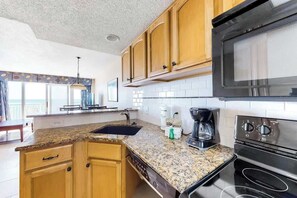 Eine Küche mit Granit-Arbeitsplatten, Holzschränken, einer schwarzen Mikrowelle und einem eingebauten Backofen.