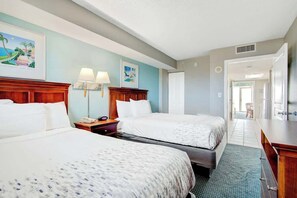A hotel room with two beds, a desk, a chair, and a bathroom visible through an open door. - Bay Watch Resort 0906 (North Myrtle Beach)