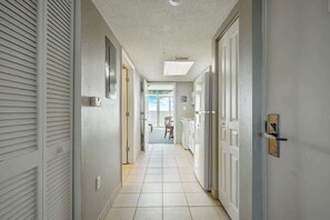 A narrow hallway with a tiled floor leading to a dining area. - Bay Watch Resort 0906 (North Myrtle Beach)