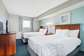 A hotel room with two beds, a wooden dresser, a television, and artwork on the walls. - Bay Watch Resort 0906 (North Myrtle Beach)