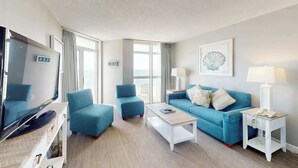 Ein Hotelzimmer mit Fernseher, einer Couch, einem Couchtisch und einer Lampe.
