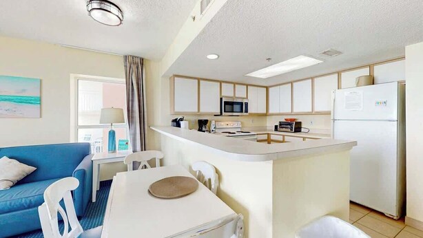 Un espacio habitable compacto con kitchenette, comedor y sofá.