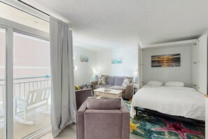 Une chambre d’hôtel avec un lit, un canapé, une chaise, une petite table et un balcon.