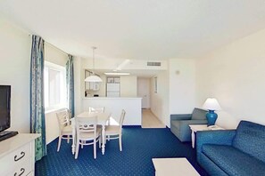 A hotel room with a dining area, a sofa, a TV, and a lamp. - Bay Watch Resort 0922 (North Myrtle Beach)