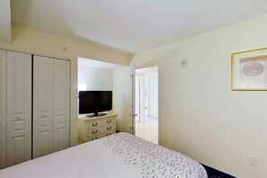 A bedroom with a bed, a television on a dresser, and a wardrobe. - Bay Watch Resort 0922 (North Myrtle Beach)