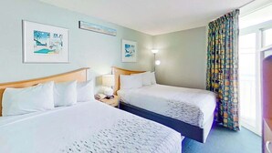 Ett hotellrum med två sängar, ett nattduksbord med en lampa och konstverk på väggarna.