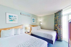 Ein Hotelzimmer mit zwei Betten, einem Nachttisch mit Lampe und Bildern an den Wänden.