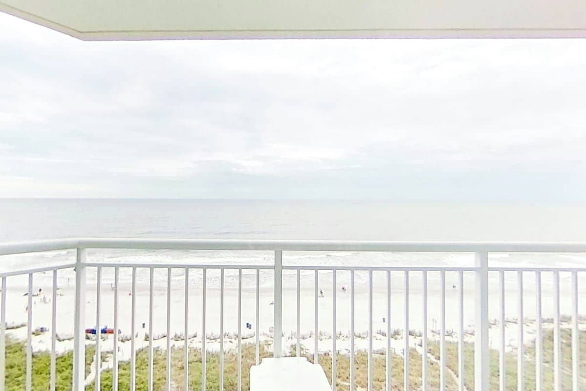A balcony with a view of the beach and ocean.