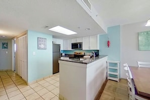 A compact kitchen with white cabinets, a microwave, and a small island with a sink. - Bay Watch Resort 1037 (North Myrtle Beach)